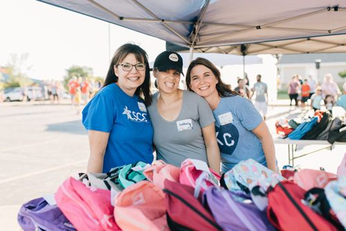group of women giving out free school supplies and backpacks